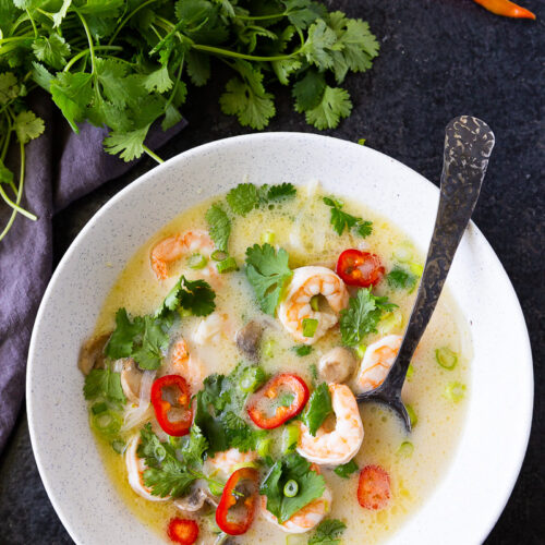 Creamy and aromatic Tom Kha soup, brimming with coconut milk, tender chicken, fresh herbs, and zesty lime, offering a comforting balance of savory, tangy, and slightly spicy flavors.