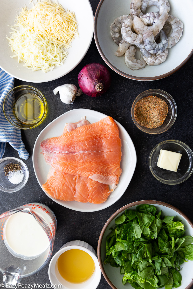 Ingredients for Cajun salmon and shrimp recipe: fresh salmon fillets, raw shrimp, Cajun seasoning, garlic, spinach, shredded cheese, cream