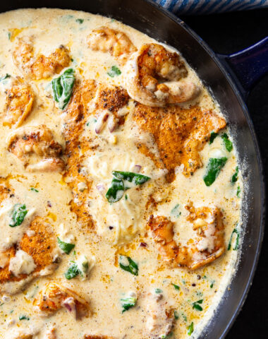 A skillet of cajun salmon and shrimp in a cheesy cream and spinach sauce.