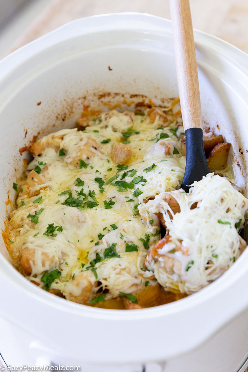 Golden brown chicken breasts coated in a creamy garlic parmesan sauce, served alongside tender baby potatoes, garnished with fresh parsley for a comforting and hearty slow cooker meal.