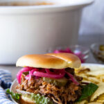 Juicy slow cooker pulled pork piled high on a soft bun, coated in rich barbecue sauce, perfect for sandwiches, sliders, or a hearty meal.