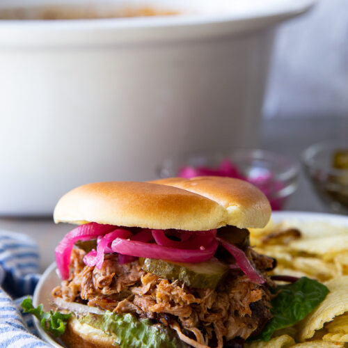 Juicy slow cooker pulled pork piled high on a soft bun, coated in rich barbecue sauce, perfect for sandwiches, sliders, or a hearty meal.