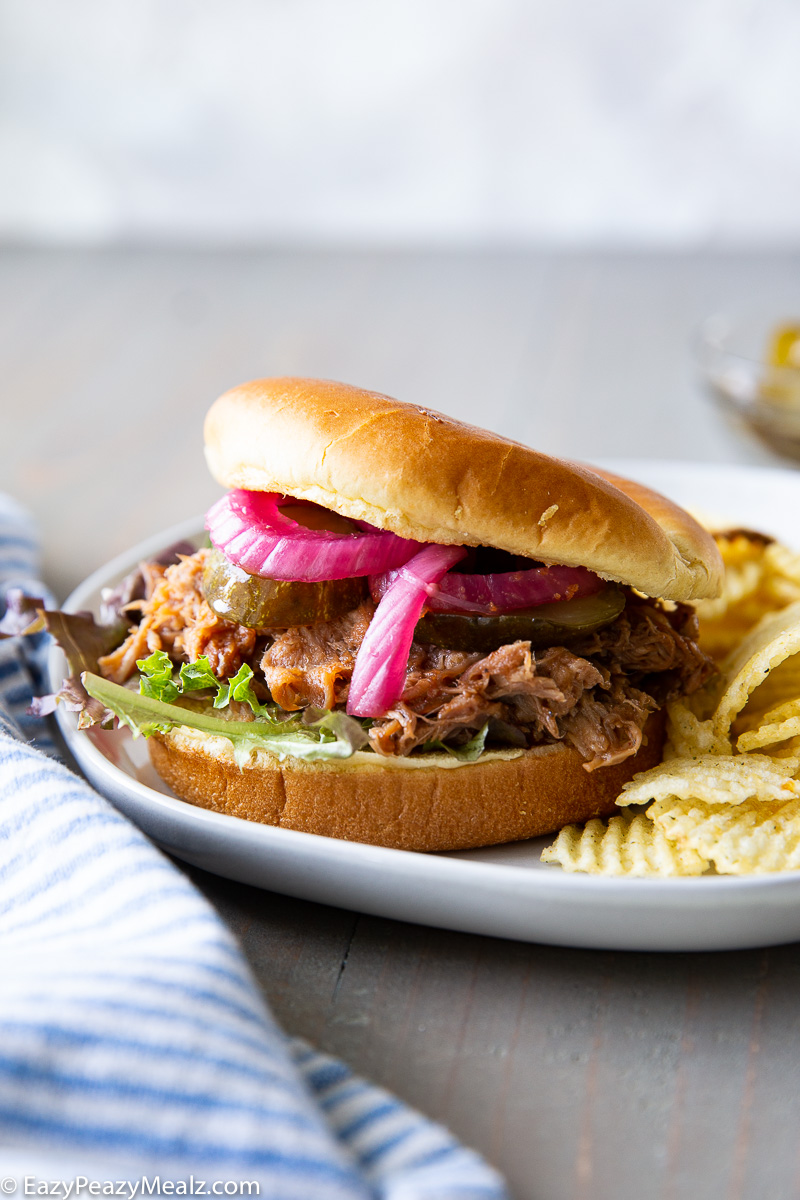Juicy slow cooker pulled pork piled high on a soft bun, coated in rich barbecue sauce, perfect for sandwiches, sliders, or a hearty meal.