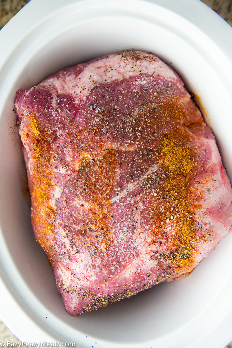 Pork shoulder seasoned and placed in the slow cooker, ready to cook low and slow