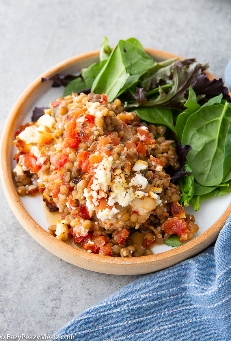A plate of baked feta chicken with bruschetta, feta, and lentils