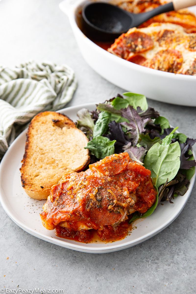 Pizza Chicken Bake on a plate with garlic bread and salad
