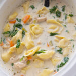 A crock full of slow cooker alfredo chicken tortellini soup