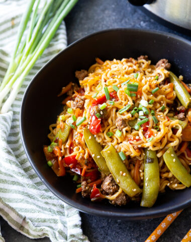 Slow cooker beef ramen stir fry topped with sesame seeds and green onion