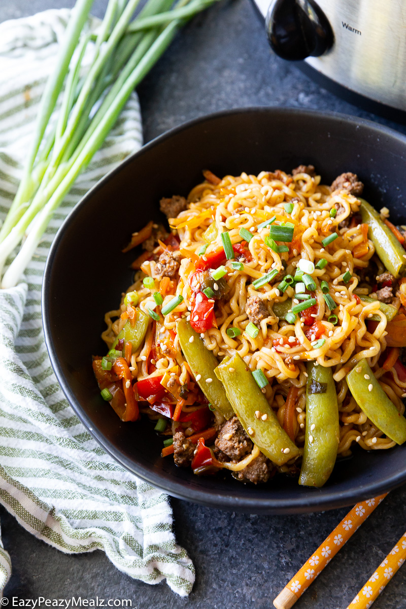 Slow cooker beef ramen stir fry topped with sesame seeds and green onion