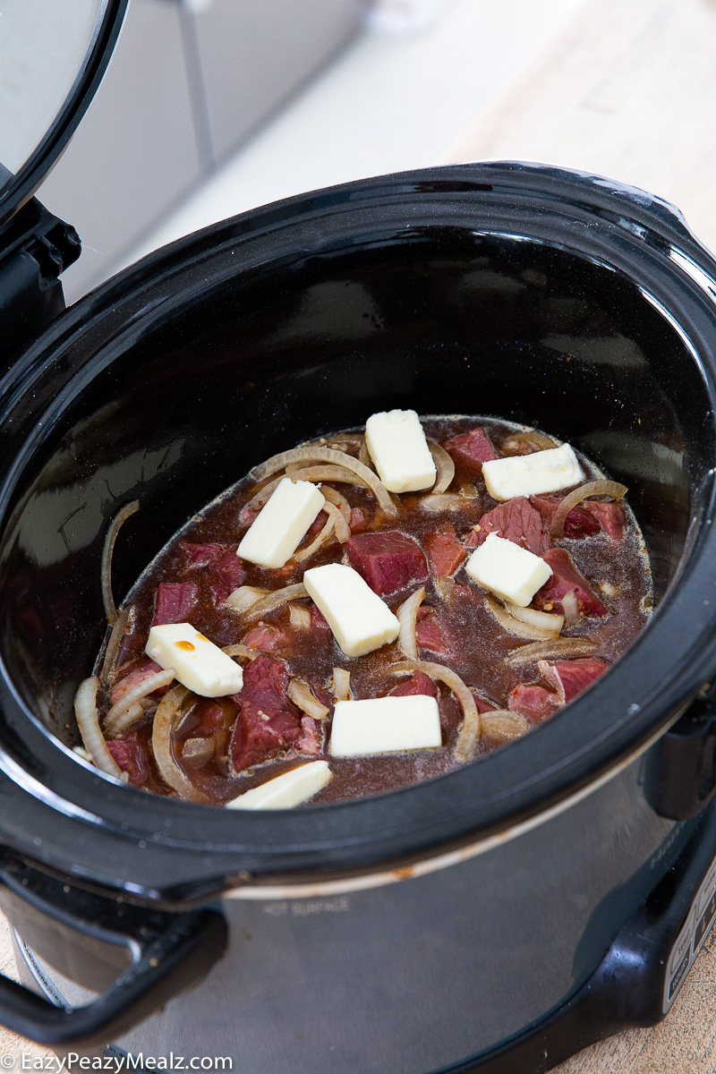 A crockpot full of slow cooker steak bites, ready to be cooked