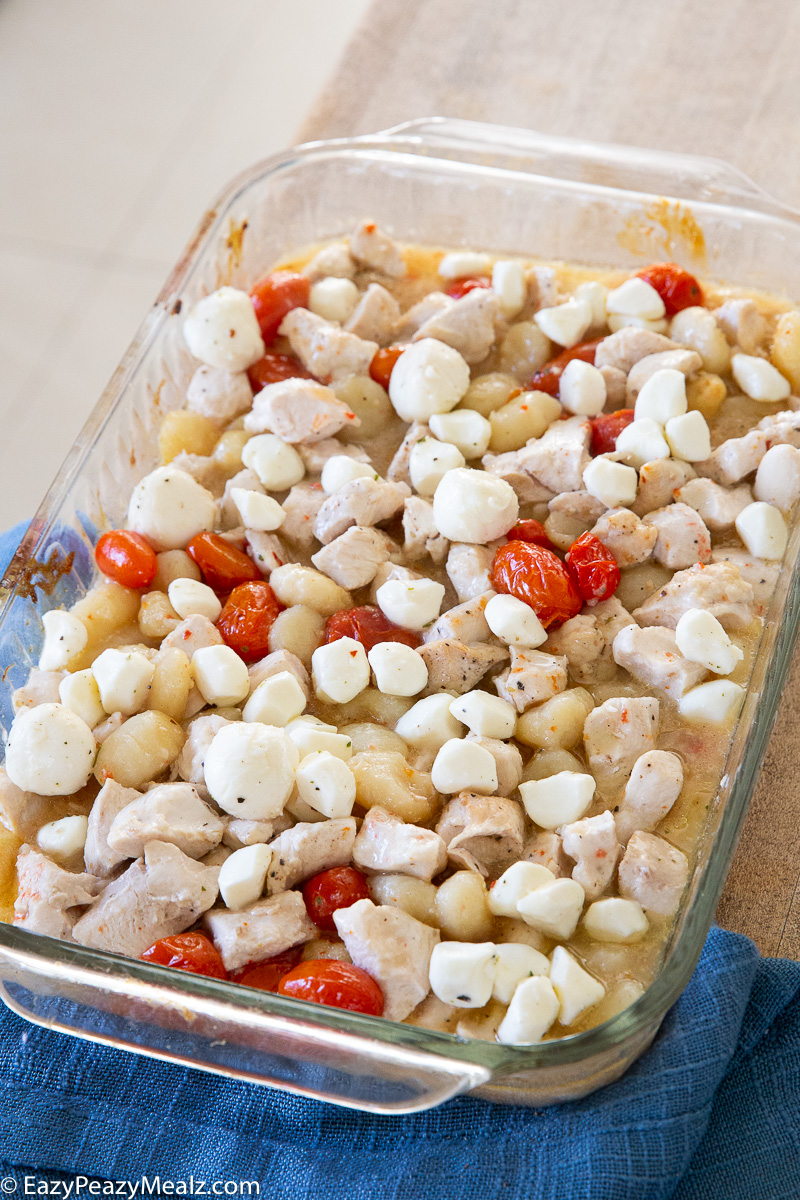 A tray full of chicken and gnocchi, tomatoes, and mozzarella.