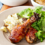 Delicious hot honey bbq chicken drumsticks cooked on a sheet pan with potatoes for a full meal.