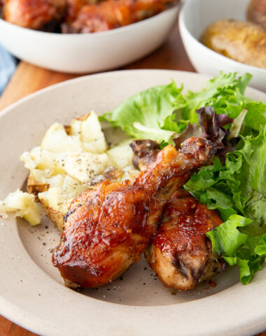 Delicious hot honey bbq chicken drumsticks cooked on a sheet pan with potatoes for a full meal.