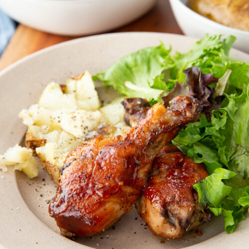 Delicious hot honey bbq chicken drumsticks cooked on a sheet pan with potatoes for a full meal.