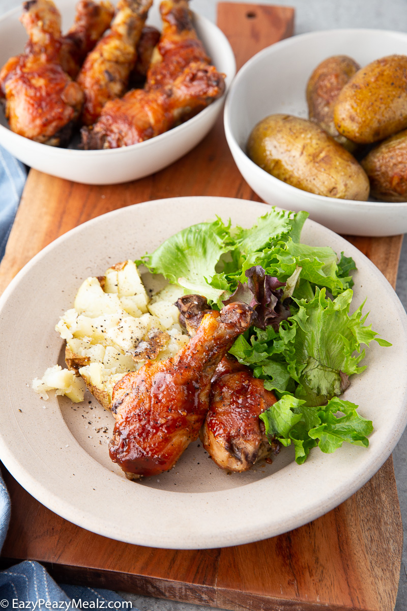 An easy one pan meal for hot honey bbq drumsticks and baked potatoes.