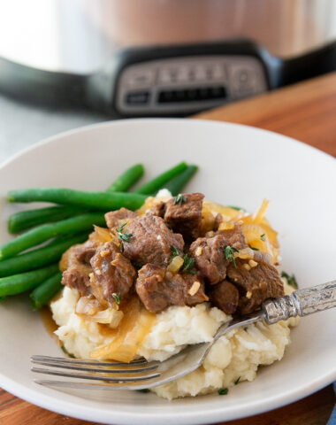 Slow cooker french onion beef tips, over creamy mashed potatoes.