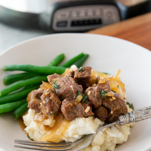 Slow cooker french onion beef tips, over creamy mashed potatoes.