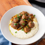 A plate full of mississippi meatballs spooned over mashed potatoes