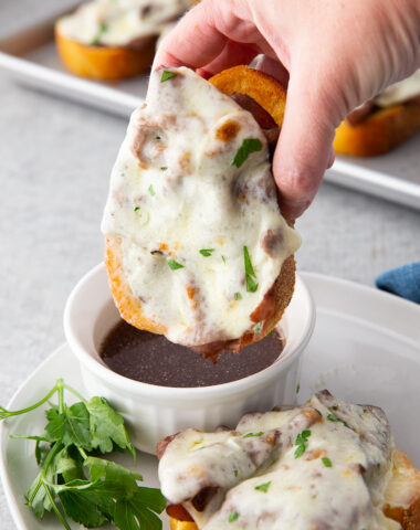 Texas toast french dip being dipped in au jus