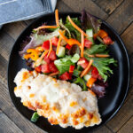 Caesar chicken bake on a plate with salad.