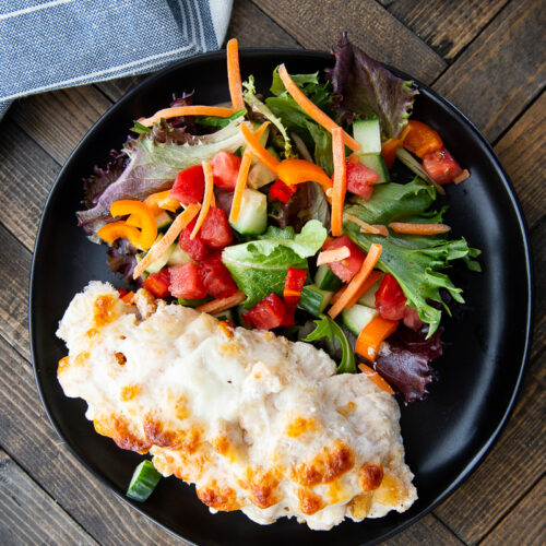 Caesar chicken bake on a plate with salad.