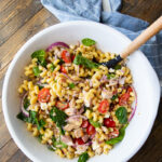 Chicken pasta salad with bacon, feta, spinach, red onion, and tomatoes.
