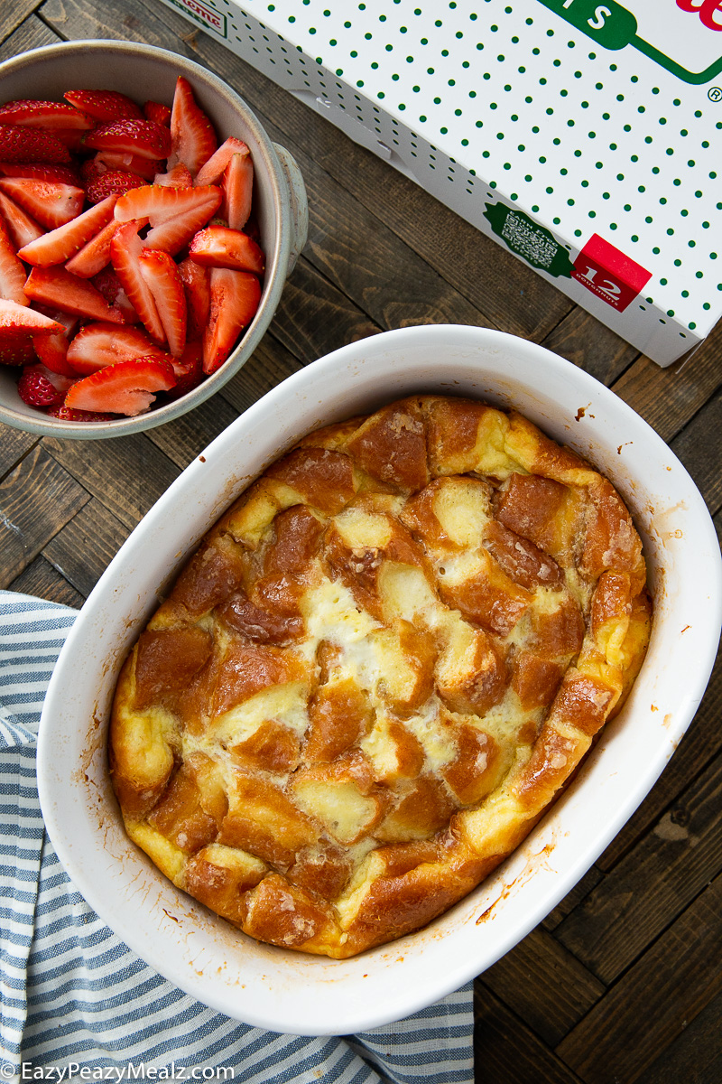 A baking dish of donut bread pudding and toppings.