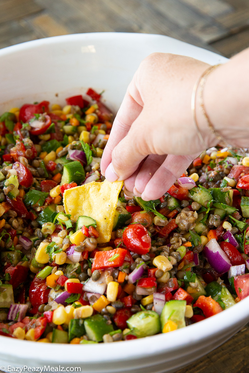 A bowl of lentil cowboy caviar being served with chips