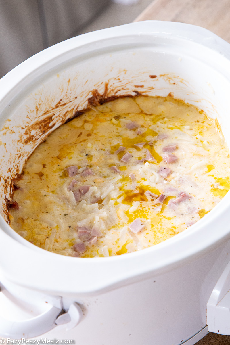 A slow cooker full of cheesy ham and potatoes.