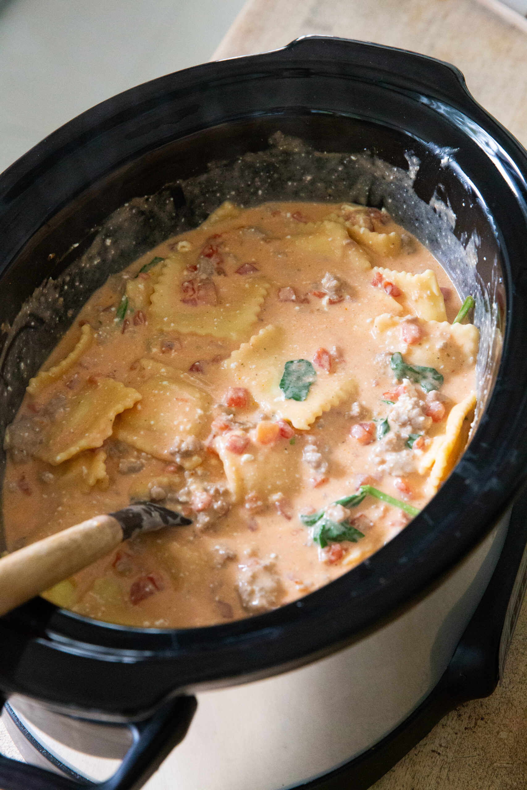 A slow cooker full of crockpot creamy sausage ravioli