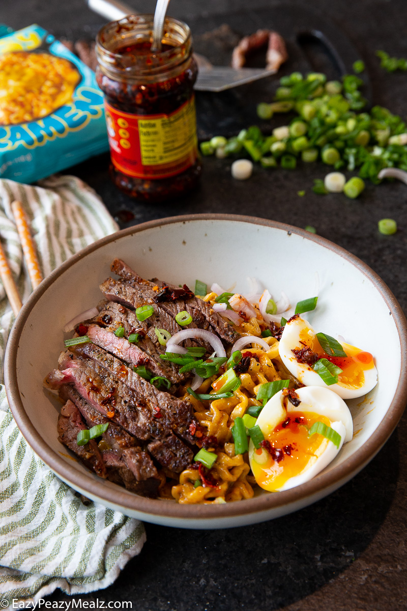 Topping cheesy ramen with steak, eggs, and green onions